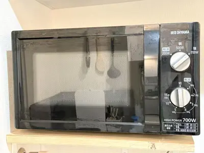 a black microwave sitting on top of a shelf at 新宿Shin-Ōkubo Aaanun 6 in Tokyo