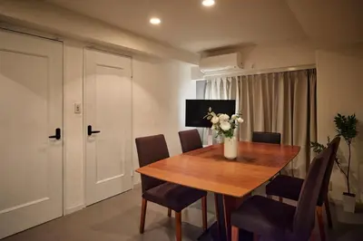 a dining room table with chairs and a vase of flowers at Tokyo Tower Roppongi walk 4 bed, Direct bus to Shibuya in Tokyo