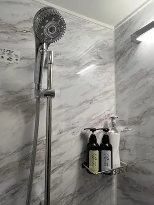 a shower head and two bottles on a shelf in a bathroom at Mitsuki in Tokyo