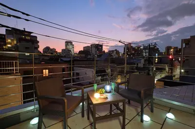 a balcony with two chairs and a table with candles at Mint House Ebisu - 3 Story, Artsy & Modern Home in Shibuya in Tokyo