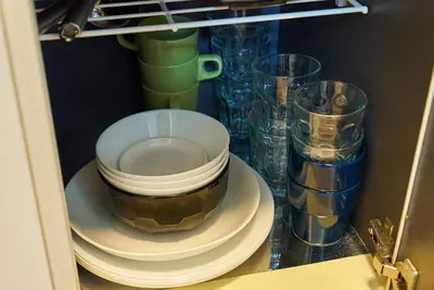 a cabinet with plates and glasses on a shelf at 11 Under the Moon Shin-Okubo Station 3 minute walk in Tokyo