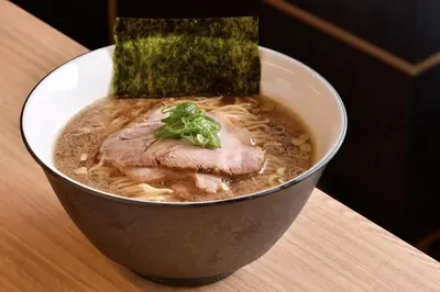 a bowl of soup with meat and a pickle on top at Blue Sky 3F in Tokyo