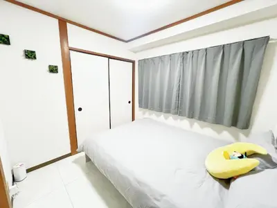a bedroom with a bed with a yellow pillow on it at \u6c60\u888b\u99c5\u96fb\u8eca4\u5206 2LDK a2 in Tokyo