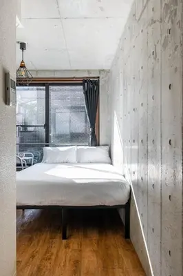 a bed in a room with a concrete wall at Cozy 1BR Apt in Asakusa-8 min walk Naka Okachimachi station in Tokyo