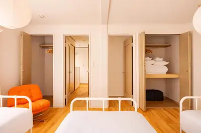 a room with two beds and an orange chair at Shinjuku Large Entire 3Story House for 9 Near 2 Stations in Tokyo