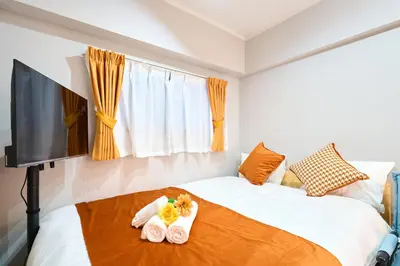 a bedroom with a bed with towels and a flat screen tv at 21sqm cozy studio 5min to JR sta Great Access to Shinjuku Shibuya in Tokyo