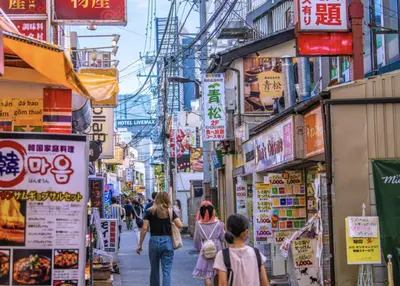 a group of people walking down a street with signs at -Gyokuran- 6-minute walk from Shin-Okubo Station in Tokyo