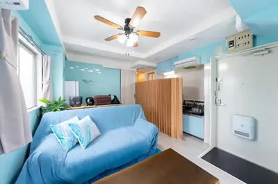 a living room with a blue couch and a ceiling fan at Tsumugi Yado \u897f\u845b\u897f in Tokyo