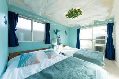 a blue bedroom with two beds and a ceiling at Tsumugi Yado \u897f\u845b\u897f in Tokyo