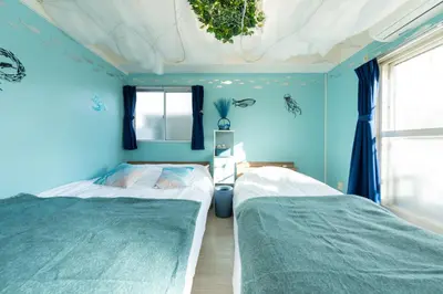 two beds in a bedroom with blue walls at Tsumugi Yado \u897f\u845b\u897f in Tokyo