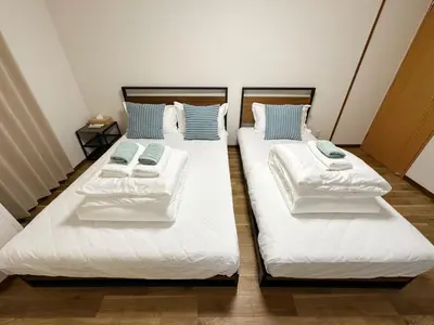 two beds in a room with white sheets and blue pillows at The Travelers Court Bunkyo II in Tokyo