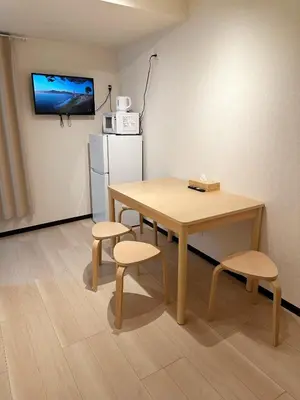 a room with a table and two chairs and a refrigerator at The Travelers Court Bunkyo II in Tokyo