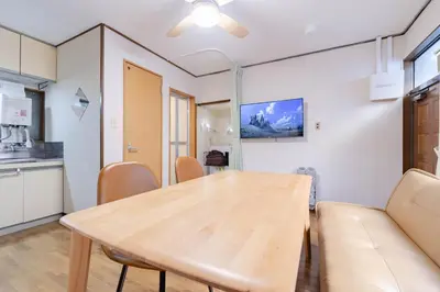 a dining room with a wooden table and chairs at Sanyouso in Tokyo