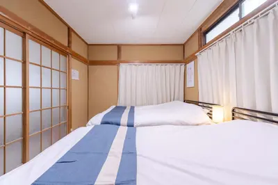 two beds in a small room with windows at Sanyouso in Tokyo