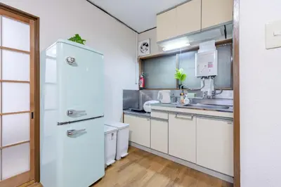 a kitchen with white cabinets and a refrigerator at Sanyouso in Tokyo