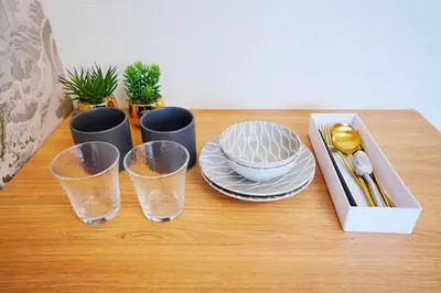 a table with three glasses and plates and a box at 10 minutes to Shibuya by train, 2 beds, great access, Yoyogi Uehara in Tokyo