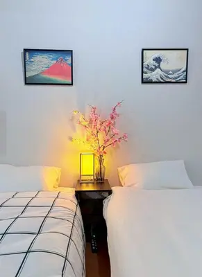 a bedroom with two beds and a table with a flower at GARDEN HOUSE Shinjuku-Sanchome 2 in Tokyo