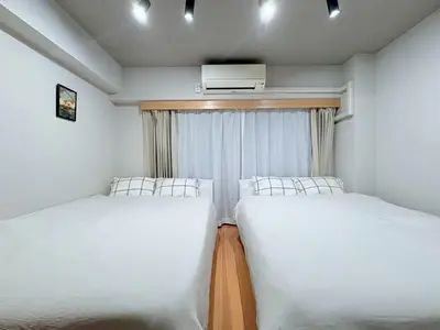 two beds in a small room with a window at GARDEN HOUSE Shinjuku-Sanchome 2 in Tokyo