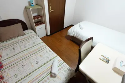 a small room with two beds and a table at Azabu House in Tokyo