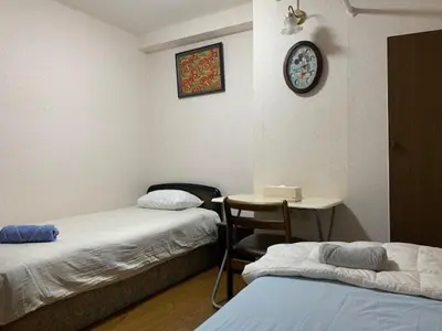 a room with two beds and a table and a clock at Azabu House in Tokyo