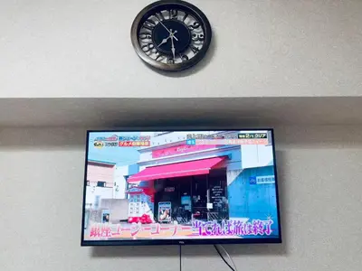 a clock on a wall next to a tv at \u6e0b\u8c37\u5bbf in Tokyo