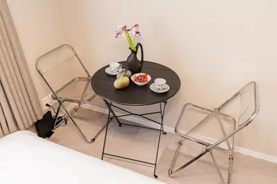 a small table with two chairs and a vase with flowers at Mi-HOTEL Kitashinjuku in Tokyo