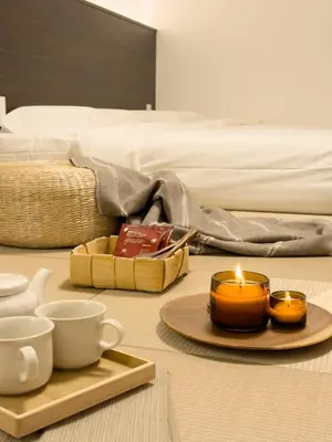 a table with a candle and cups and a bed at ISSHUKU NOMA\u6c60\u888bII 101 - Spacious Room for 5 Guests in Tokyo