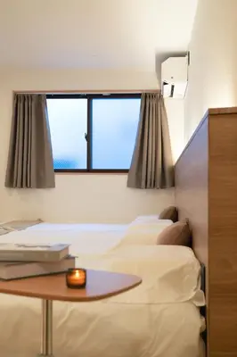a room with two beds and a table and a window at ISSHUKU Noma \u5317\u65b0\u5bbfI -302 Quad Room in Tokyo