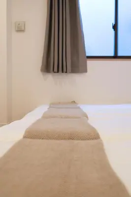 a row of pillows on a bed with a window at ISSHUKU Noma \u5317\u65b0\u5bbfI -302 Quad Room in Tokyo