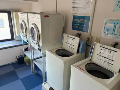 two washing machines sitting in a laundry room at \u99c5\u5f92\u6b695\u5206 Sugamo Yasu Hotel in Tokyo