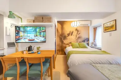 a room with two beds and a wooden table at \u99c5\u5f92\u6b695\u5206 Sugamo Yasu Hotel in Tokyo