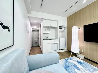 a living room with a couch and a tv and a kitchen at Kabukicho Designer's Apt X in Tokyo