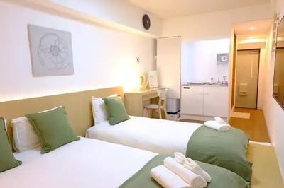 two beds in a hotel room with a kitchen at Shinjuku Kabukicho Apt XI in Tokyo