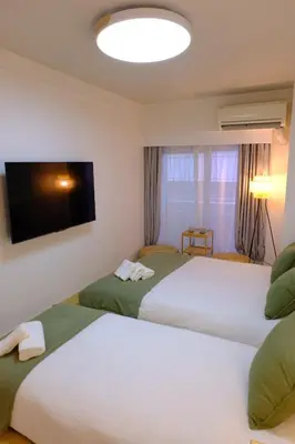 two beds in a hotel room with a flat screen tv at Shinjuku Kabukicho Apt XI in Tokyo