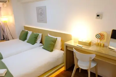 a room with two beds and a desk and a chair at Shinjuku Kabukicho Apt XI in Tokyo