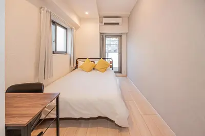 a bedroom with a bed and a desk and a window at Louis stage asakusa in Tokyo