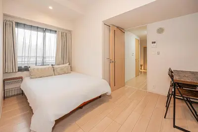 a white bedroom with a bed and a window at Louis stage asakusa in Tokyo