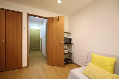 a room with a bed and a door with a yellow pillow at Hatsudai Guest House GRINDEL in Tokyo
