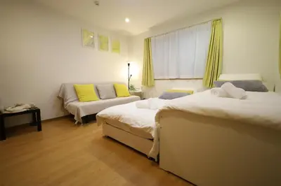 a hotel room with two beds and a couch at Hatsudai Guest House GRINDEL in Tokyo