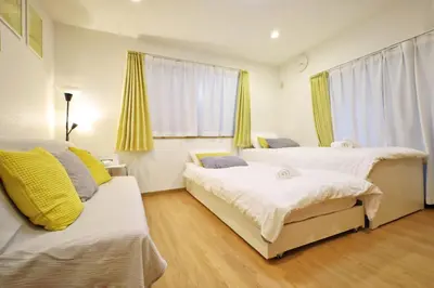 a bedroom with two beds and a couch at Hatsudai Guest House GRINDEL in Tokyo