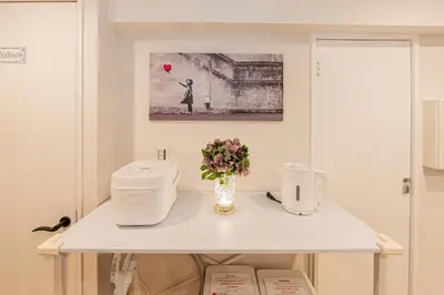 a white table with a vase of flowers on it at 80m to Aoto Station Elevator Access 35 Min Direct to Haneda Airport Direct Train to Narita Airport Easy Access to Ginza Asakusa Disney Skytree Convenience Store and Pharmacy Downstairs in Tokyo