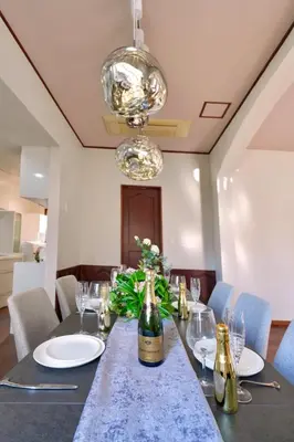 a dining room with a table with a bottle of champagne at New Open! Shinjuku 5 bedrooms 3 bathrooms Large Villa 2000 sq ft, kids play room, max 16ppl, 4min train to Shinjuku - Magnolia Hotel Shinjuku in Tokyo