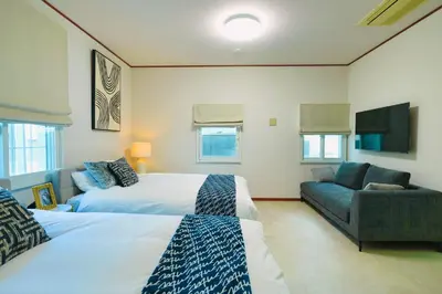a bedroom with two beds and a couch and a television at New Open! Shinjuku 5 bedrooms 3 bathrooms Large Villa 2000 sq ft, kids play room, max 16ppl, 4min train to Shinjuku - Magnolia Hotel Shinjuku in Tokyo
