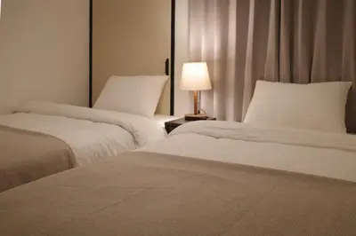 two beds in a room with a lamp on a table at \u6cca\u5bb6\u6771\u795eHakuya toshin in Wada