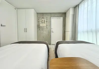 a bedroom with two beds and a wooden table at 102Room,7-minute walk from Uguisudani Station located on the 1nd floor of an apartment-style building Twin room No elevator in Tokyo