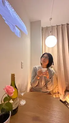 a woman sitting at a table drinking from a cup at Moon Base Tokyo Inn in Tokyo