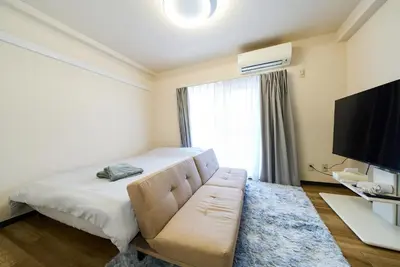 a bedroom with a bed and a couch and a television at 22\u30e1\u30be\u30f3\u30b8\u30e5\u30cd\u30b9 in Tokyo