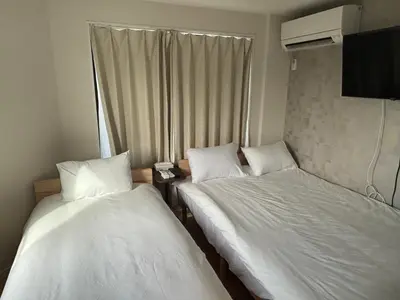 two beds in a small room with white sheets at \u3055\u304f\u3089\u65c5\u9928\u9ad8\u5186\u5bfa\u5317\u5343\u5229\u4f11302\u53f7\u5ba4 in Tokyo