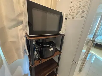 a microwave on a shelf next to a refrigerator at \u3055\u304f\u3089\u65c5\u9928 \u9ad8\u5186\u5bfa\u5317 \u5343\u5229\u4f11401\u53f7\u5ba4 in Tokyo