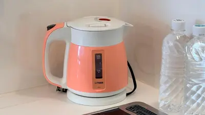 an orange and white blender on a counter with a bottle of water at YIYou Japan\u79cb\u8449\u539f401 in Tokyo